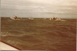 visserskotters, de begeleidende boten, hebben moeite met de hoge golven